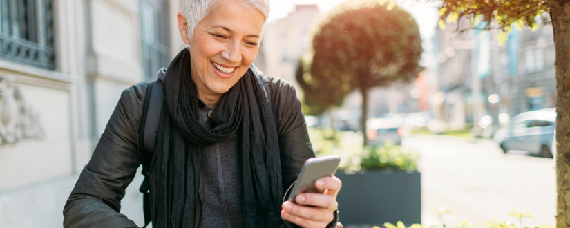 woman smiling while looking at mobile phone